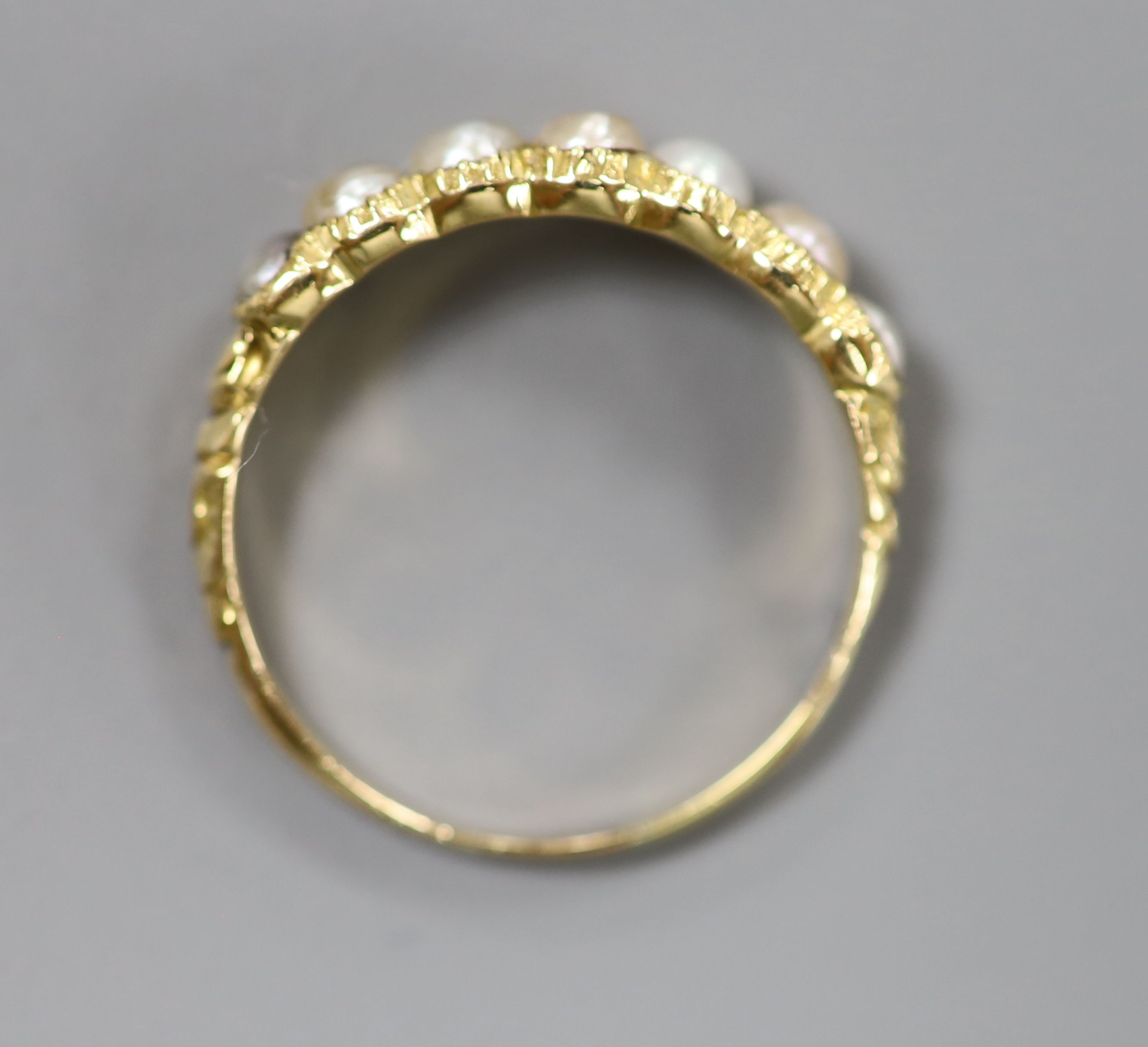 A late Victorian yellow metal and split pearl set half hoop ring